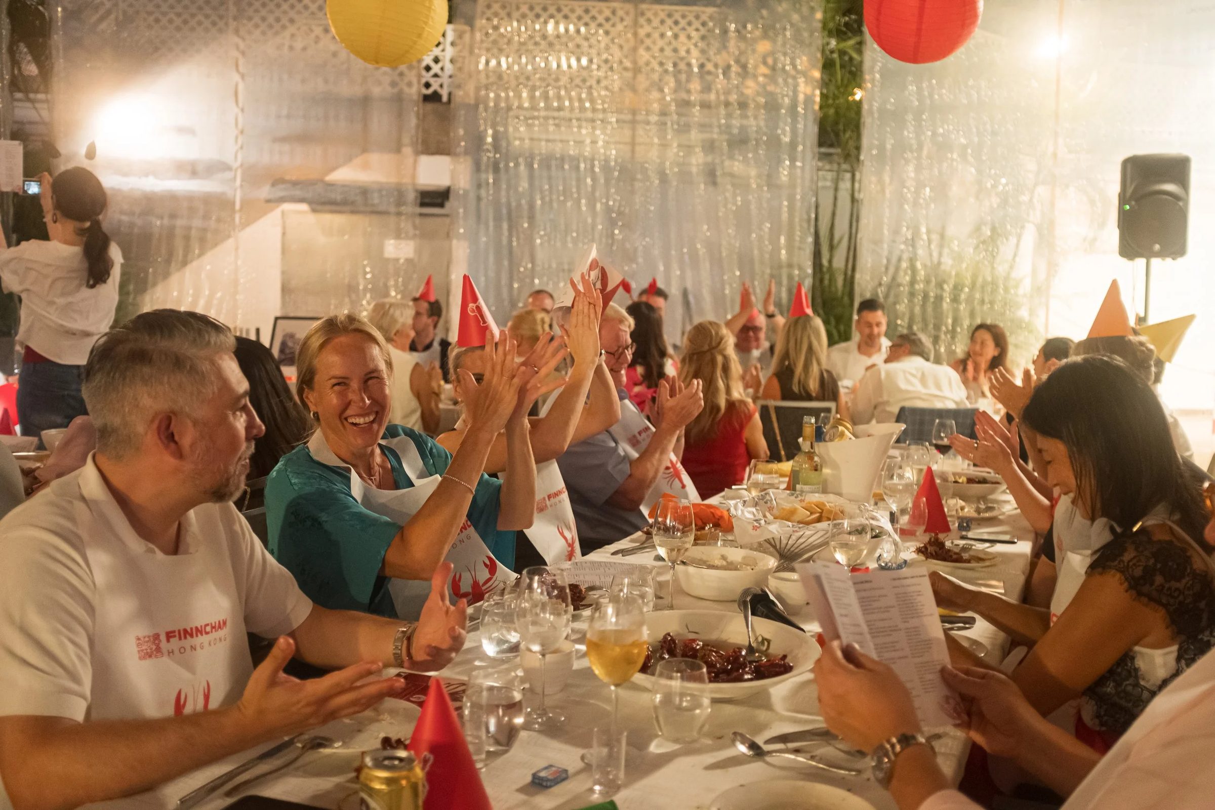 Guests in party hats cheering at the long tables of the Crayfish Party